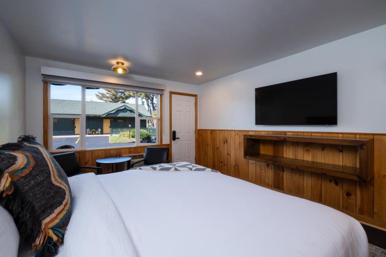 A bed in a room with wood paneling and a tv.