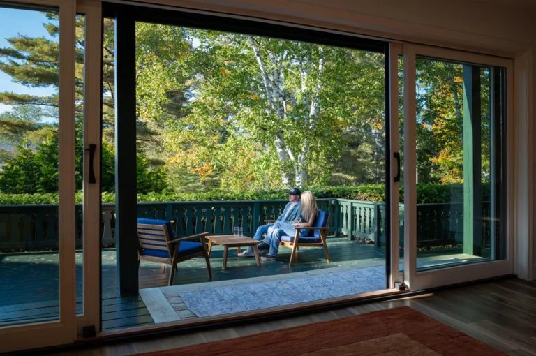 A woman sitting on a chair in front of a sliding glass door.