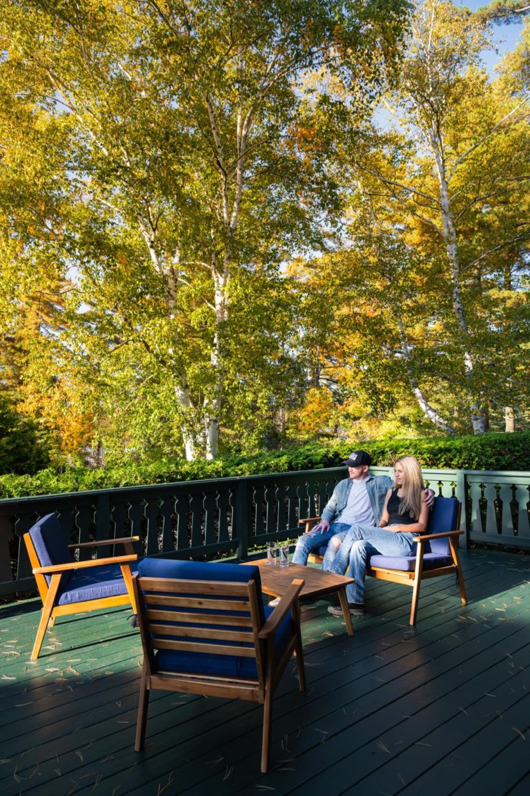 Two people sitting on a deck with trees in the background.