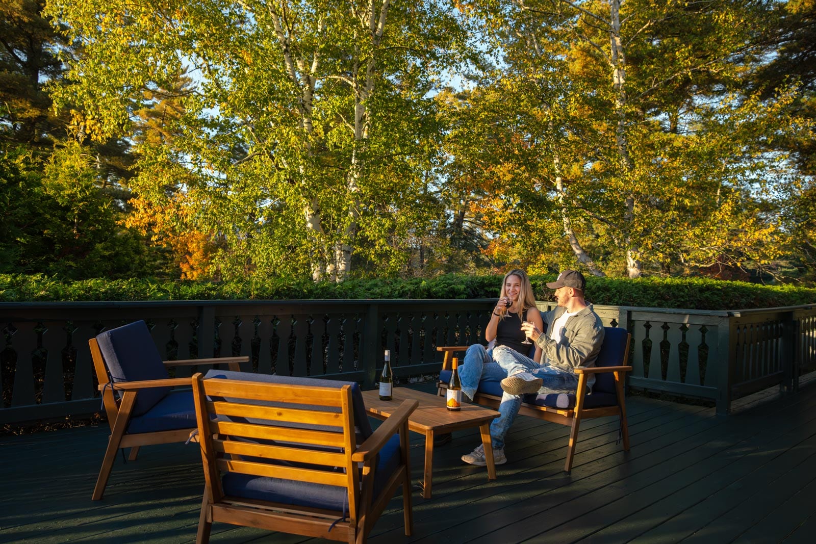 Two people sitting on a deck in the fall.