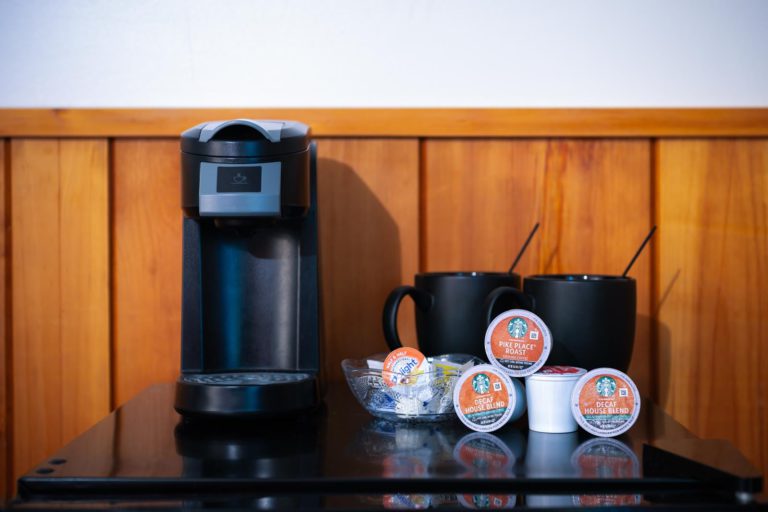 A keurig coffee maker sits on a table next to a cup of coffee.