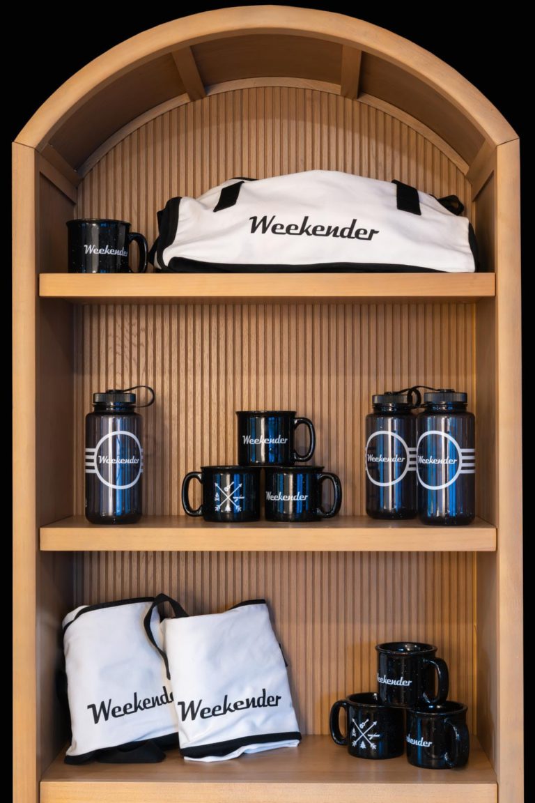 A wooden shelf with mugs and other items on it.