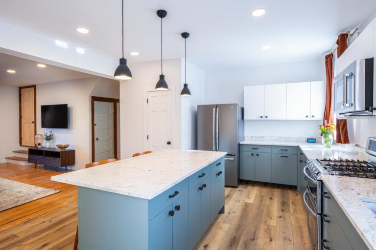 A kitchen with a blue island and hardwood floors.