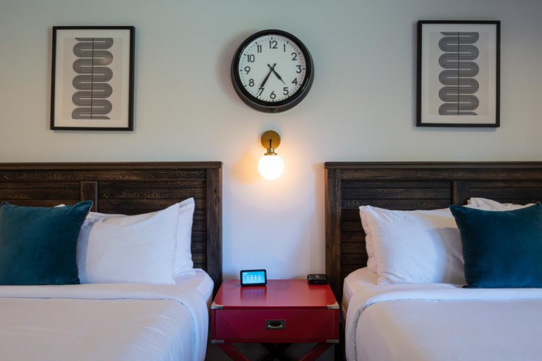 Two beds in a room with a clock on the wall.