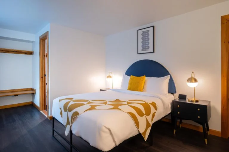 A bed in a room with wooden floors and a yellow headboard.