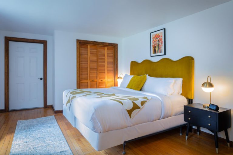 A bed in a bedroom with a yellow headboard.