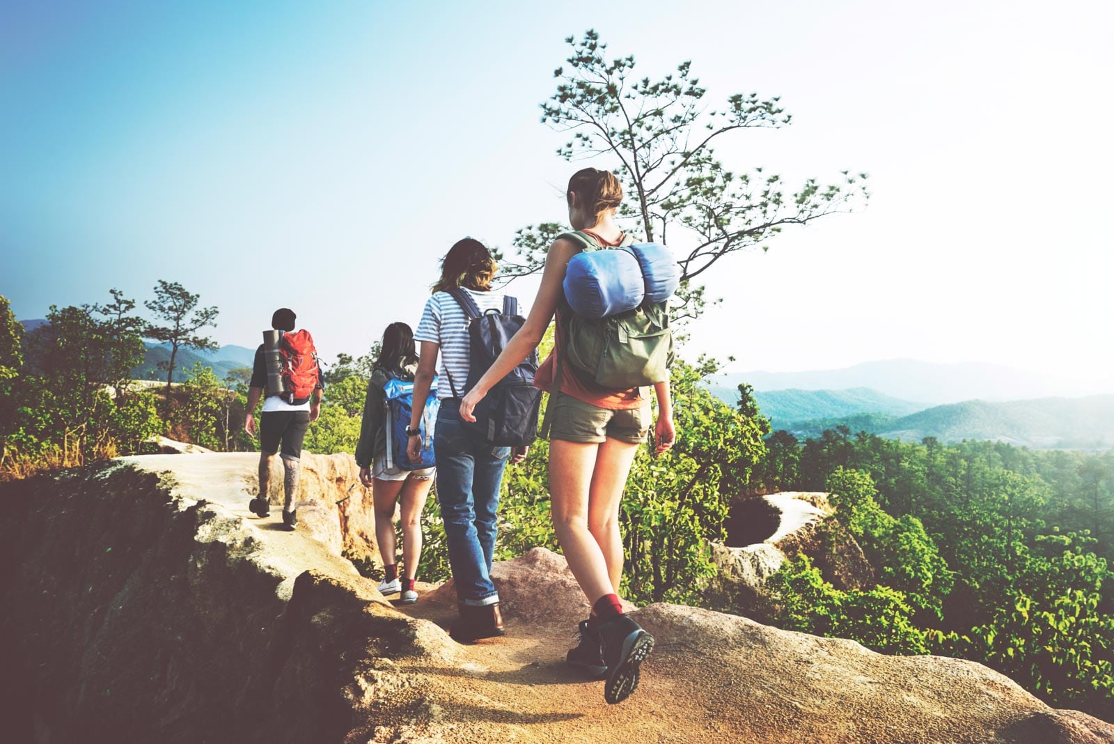 A group of people hiking with backpacks on a rocky cliff.