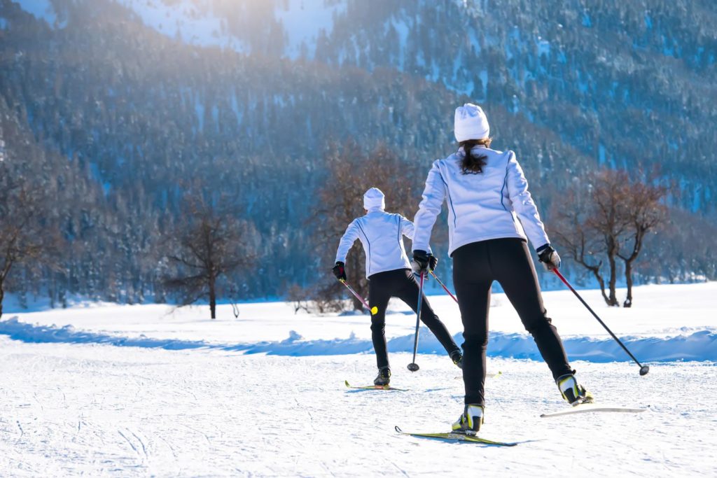Two people cross country skiing in the snow.