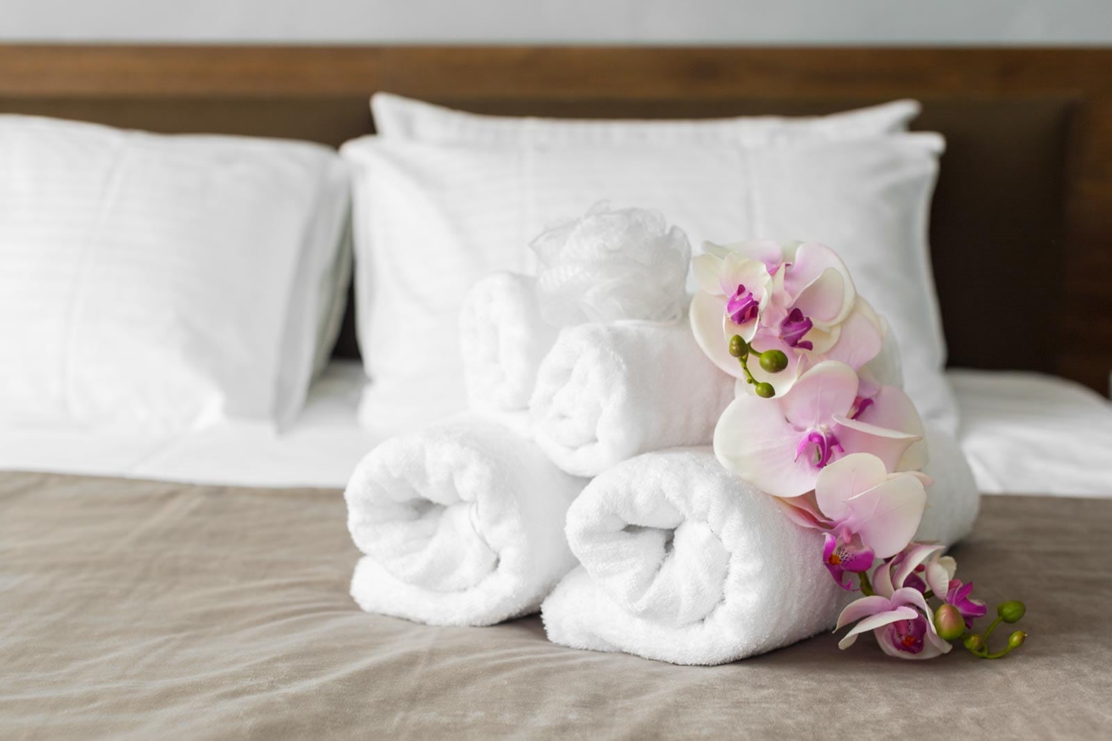 A stack of white towels on a bed with orchids.